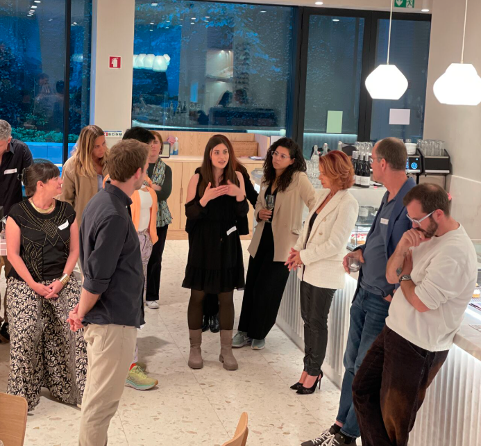 Miriam Elia in conversation with a small group of professionals at an evening networking event